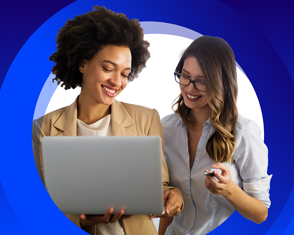 Two smiling young woman looking at a laptop together