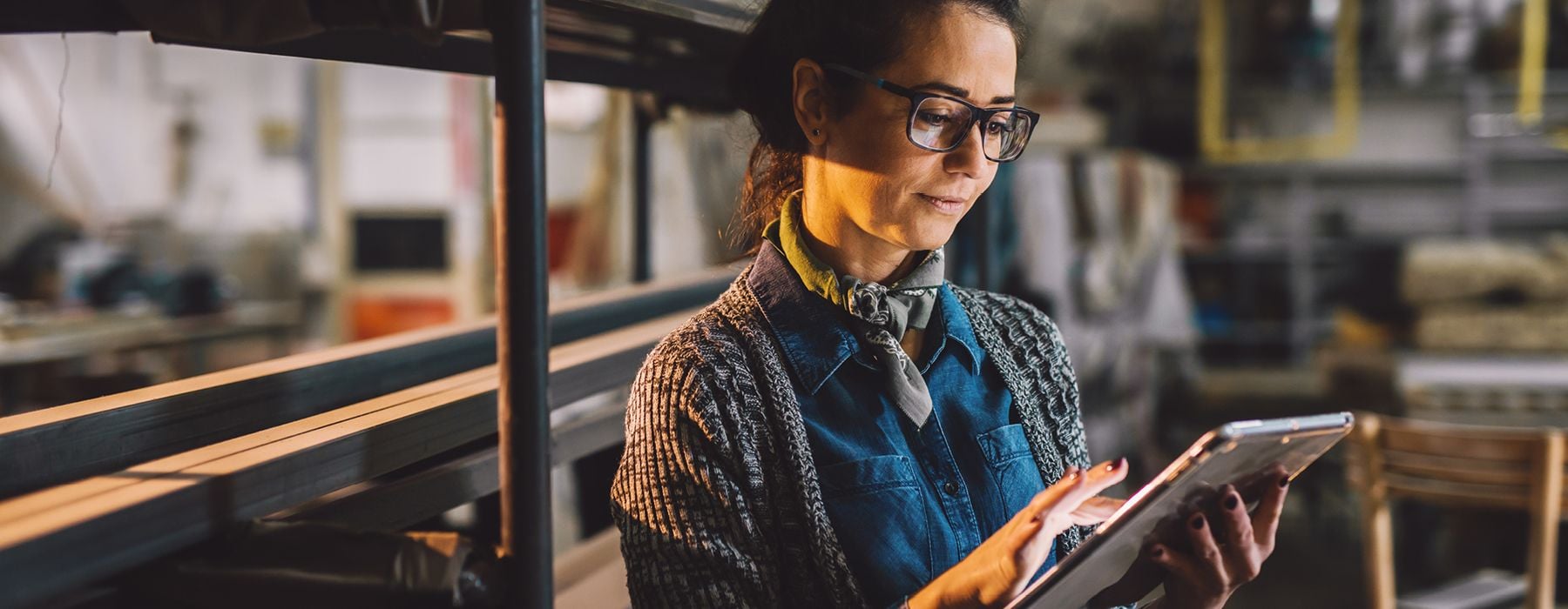 Image of a woman in a warehouse holding a laptop