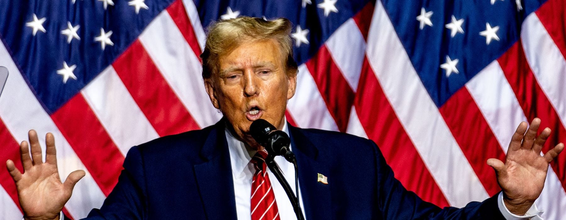 Image of President Donald Trump at a podium with American flags as the backdrop