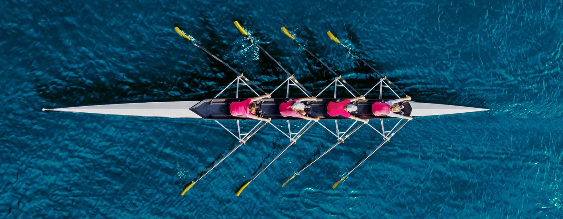 Top down image of 4 rowers operating a boat together