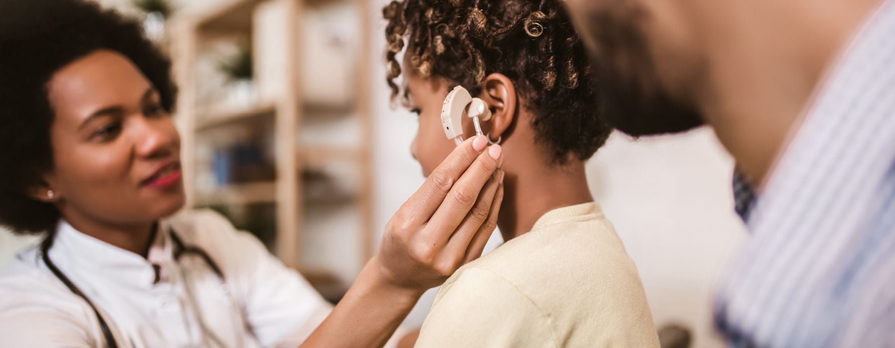 Medical practitioner checking a child's hearing aid